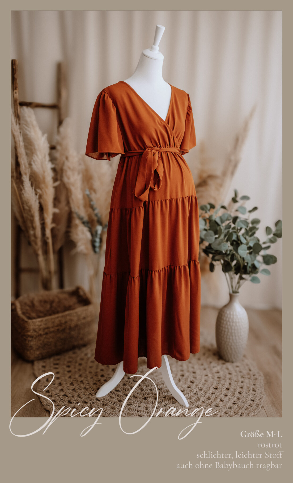 Ein rostorangefarbenes, kurzärmeliges, gestuftes Midikleid mit Bindeband in der Taille ist auf einer weißen Schaufensterpuppe ausgestellt. Im Hintergrund sind Pampasgras, ein geflochtener Korb und eine Vase mit Grünzeug in einem sanft beleuchteten Raum zu sehen.