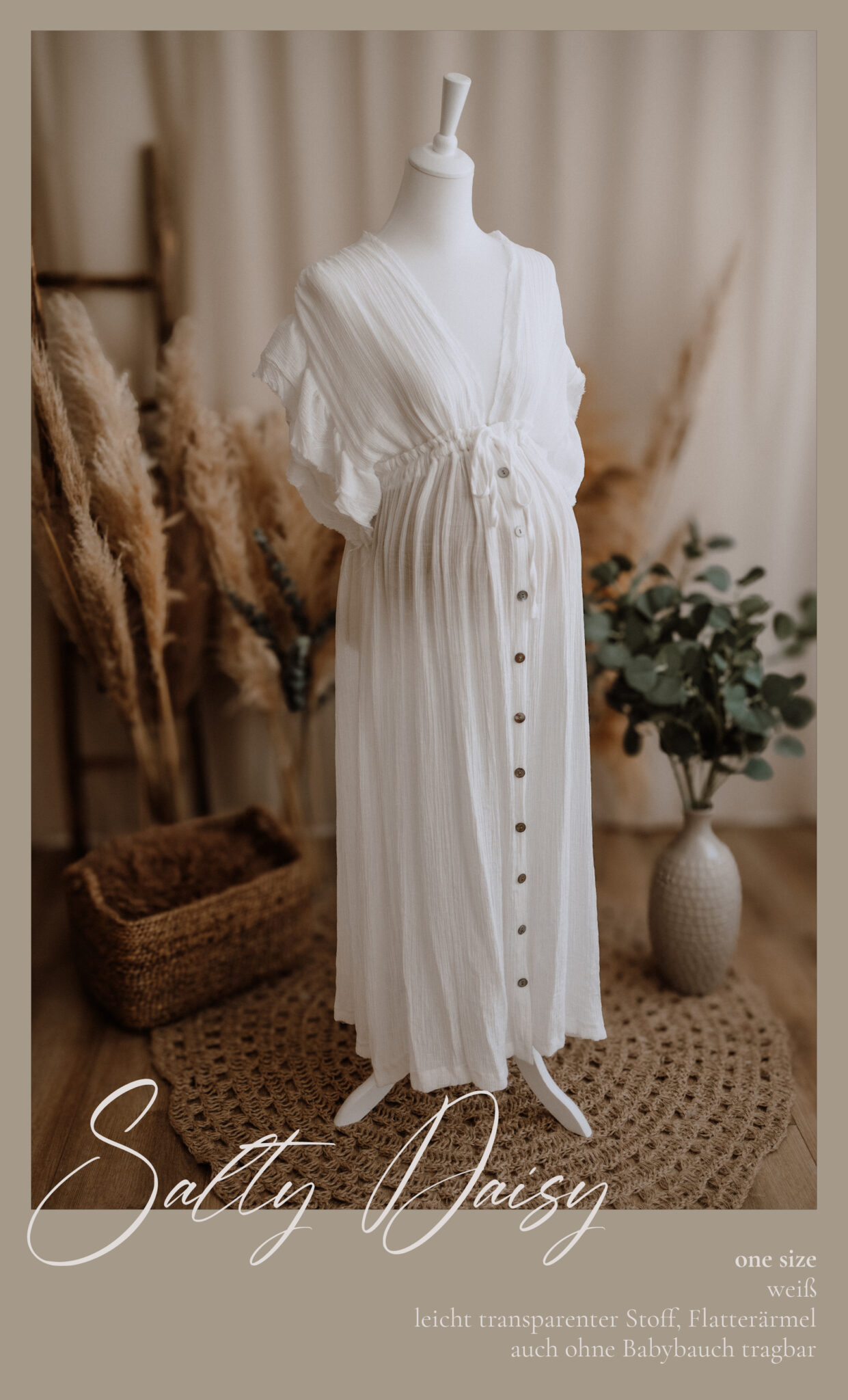 Ein weißes, fließendes, geknöpftes Umstandskleid ist auf einer Schaufensterpuppe ausgestellt, umgeben von Pampasgras, einem geflochtenen Korb und einer grünen Topfpflanze in einem gemütlichen, neutral getönten Raum. Am unteren Rand erscheinen Textüberlagerungen.