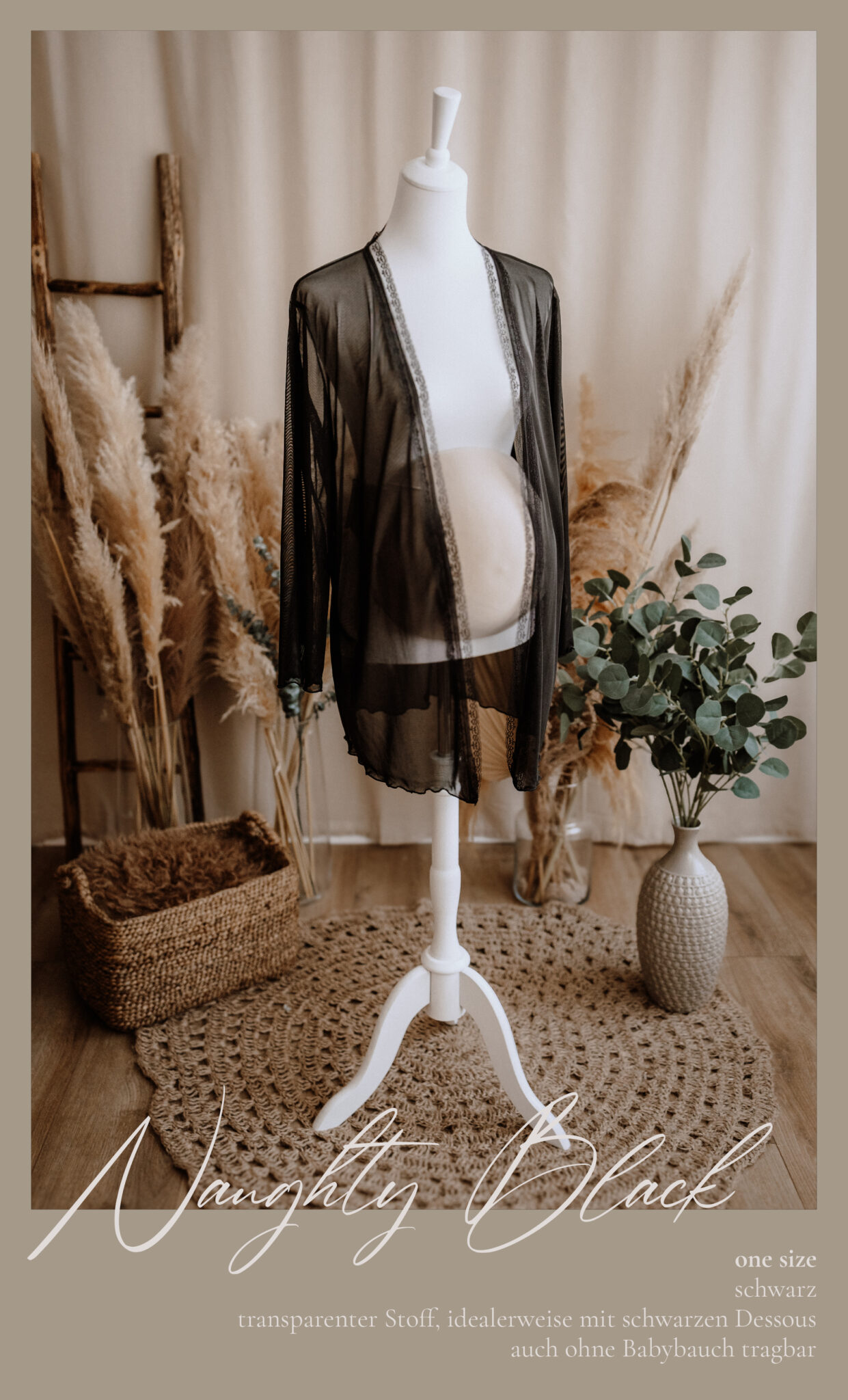 Ein schwarzer, durchsichtiger Umstandsmantel ist auf einer weißen Schaufensterpuppe in einem gemütlichen Raum mit Pampasgras und geflochtenen Körben ausgestellt. Der Text lautet: "Naughty Black Einheitsgröße, schwarz, transparenter Stoff, idealerweise mit schwarzen Dessous, auch ohne Babybauch tragbar.